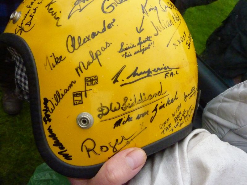 Side view of yellow crash helmet showing a number of signatures in black of various balloon pilots.
